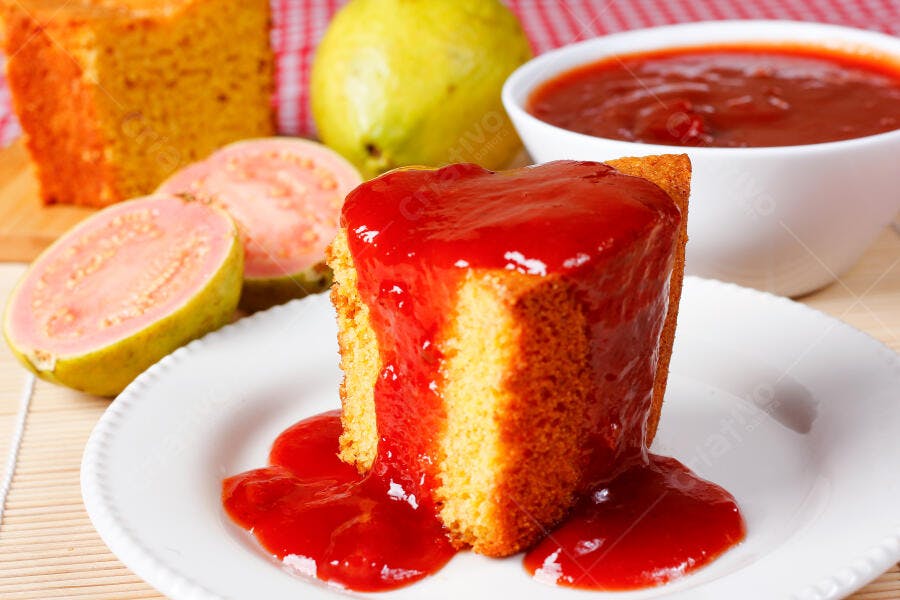 Fatia de bolo de fubá com calda de goiabada goiaba fresca em prato branco