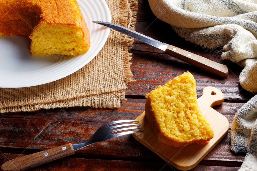 Fatias de bolo de fubá milho na mesa rústica com faca e garfo sobre estopa