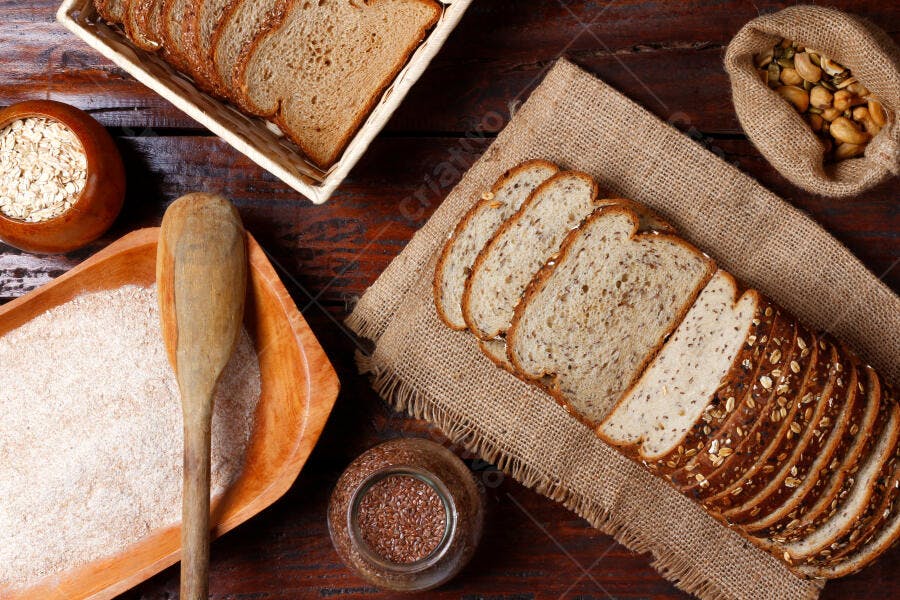 Pão integral fatiado com sementes e aveia em mesa rústica de madeira