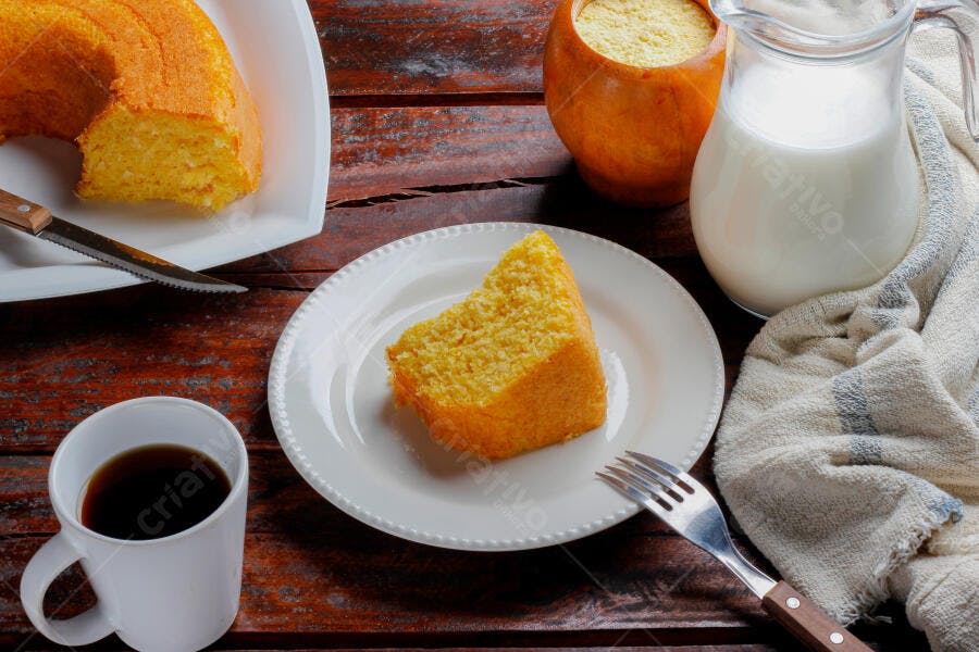 Bolo de milho fofo amarelo fatia com café e leite na mesa rústica