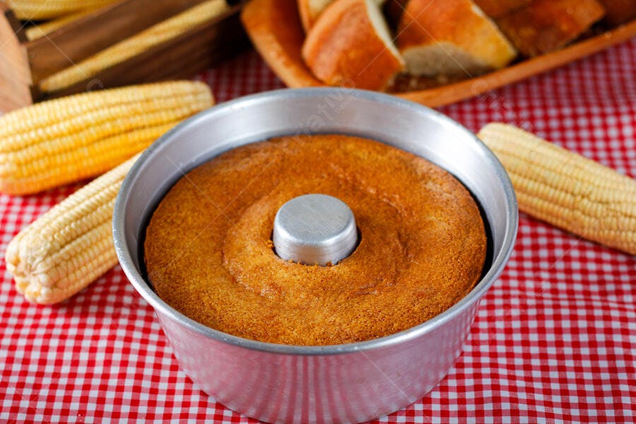Bolo de milho fofo em forma redonda com espigas na mesa xadrez