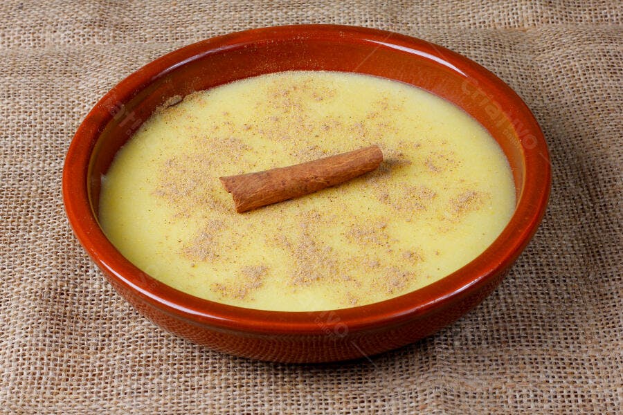 Curau de milho cremoso com canela em tigela rústica sobre juta