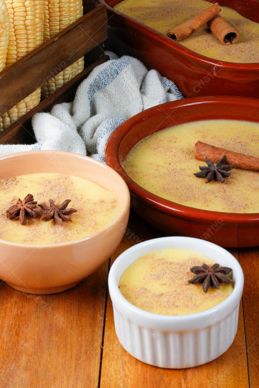 Canjica amarela cremosa com anis estrelado e canela em tigelas rústicas sobre madeira