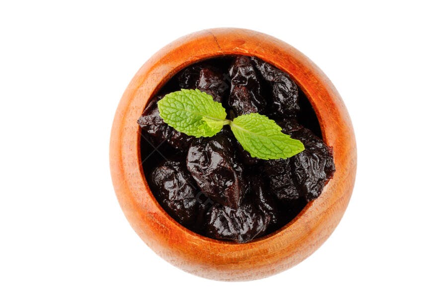 Ameixas secas em tigela de madeira com hortelã fresca