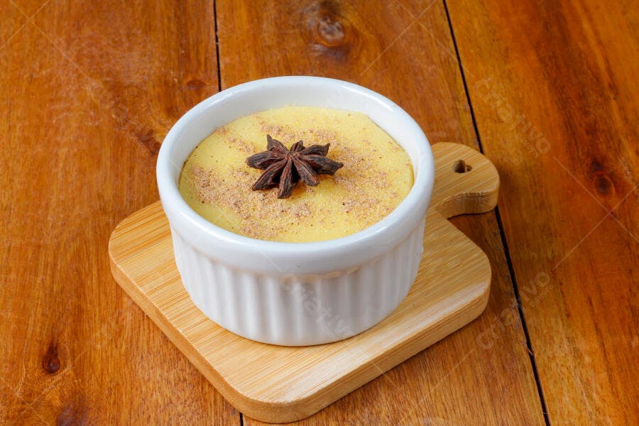 Pudim cremoso de milho com canela e anis estrelado em mesa de madeira