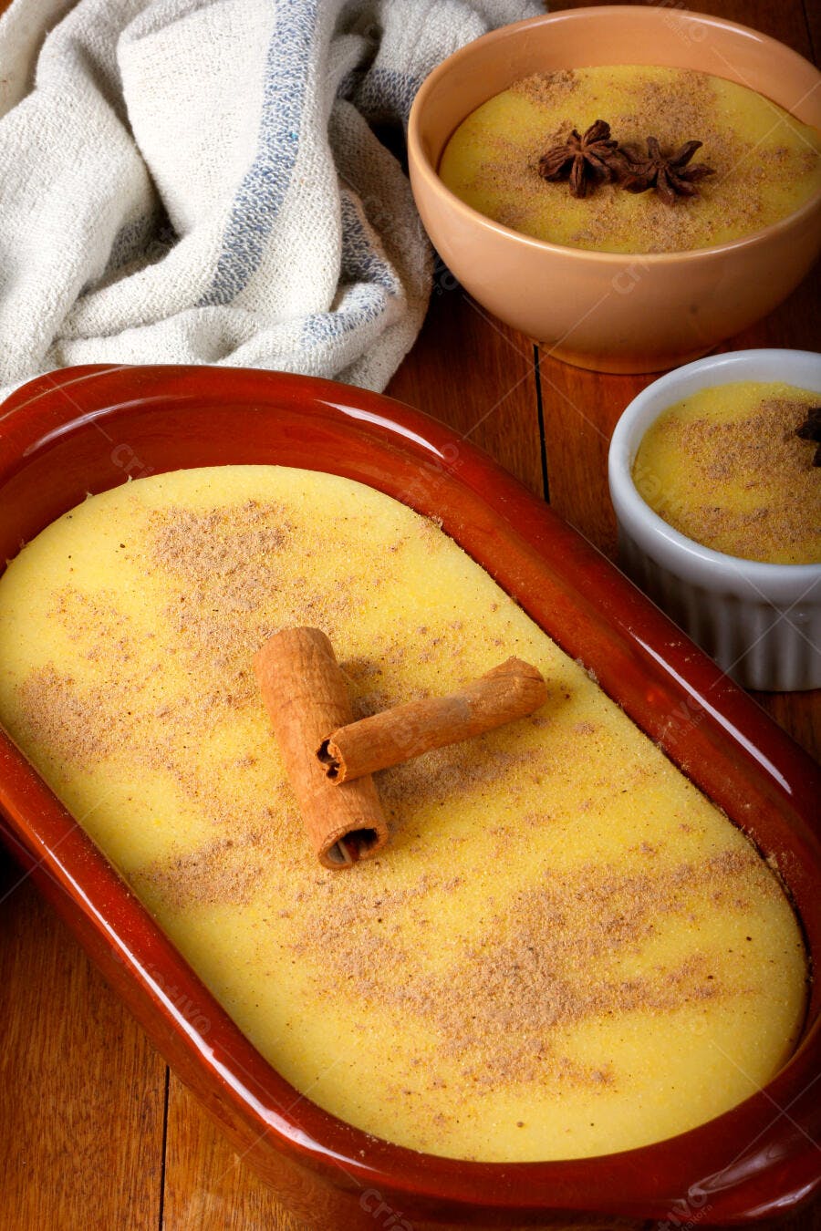 Curau de milho cremoso em travessa de barro rústica com canela e anis