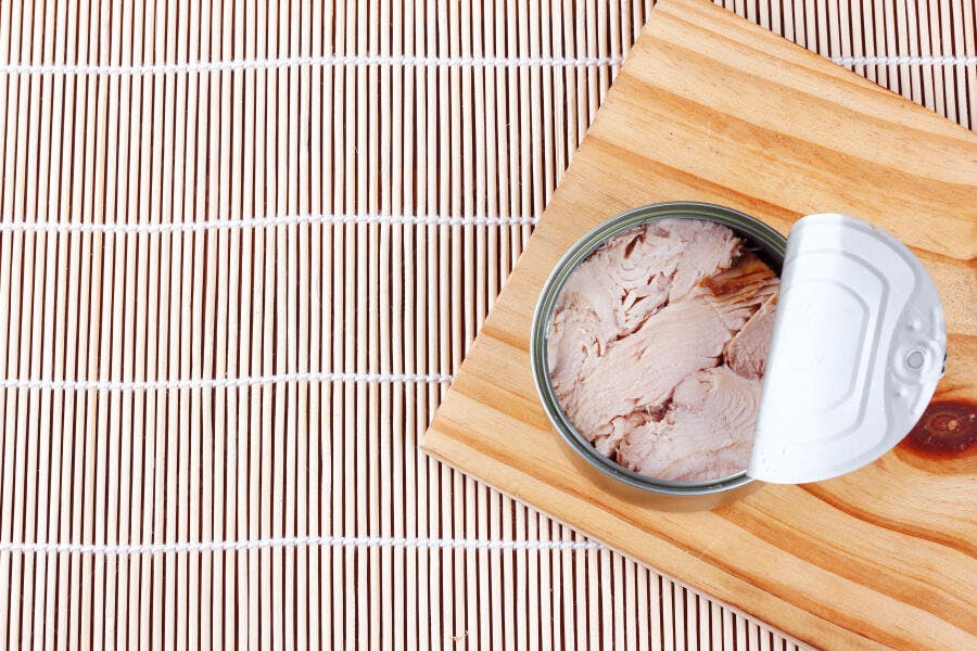 Lata de atum aberta alimento nutritivo sobre esteira de bambu