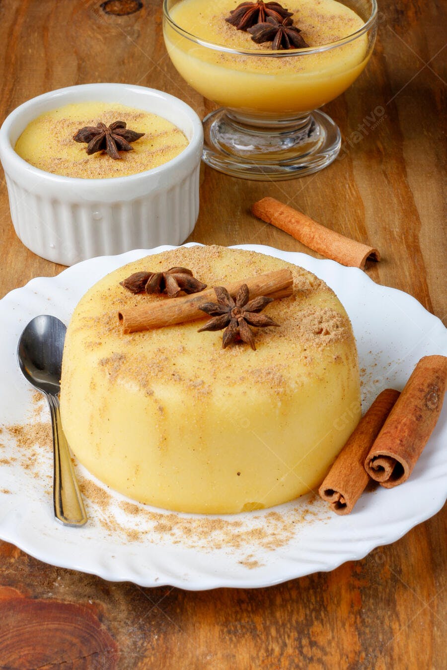 Curau cremoso amarelo com canela em pau e anis estrelado sobre madeira