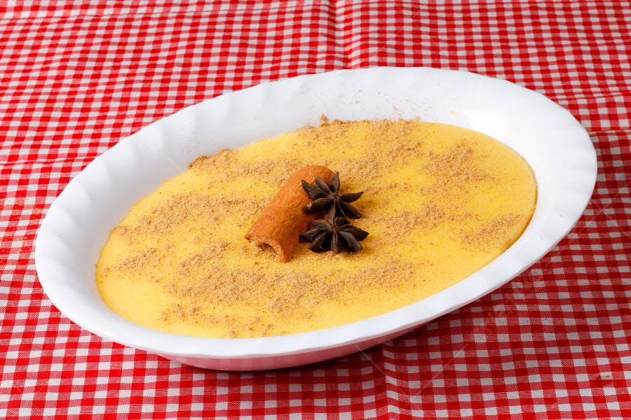Curau de milho cremoso amarelo com canela e anis estrelado em toalha xadrez