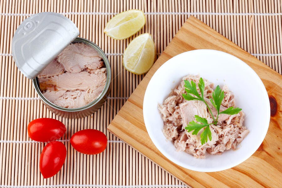 Atum em lata e em tigela com limão tomates e salsinha