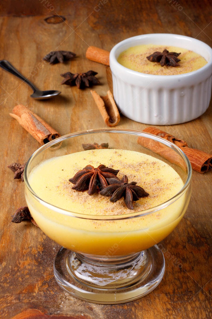 Pudim cremoso amarelo com anis estrelado e canela em mesa de madeira rústica