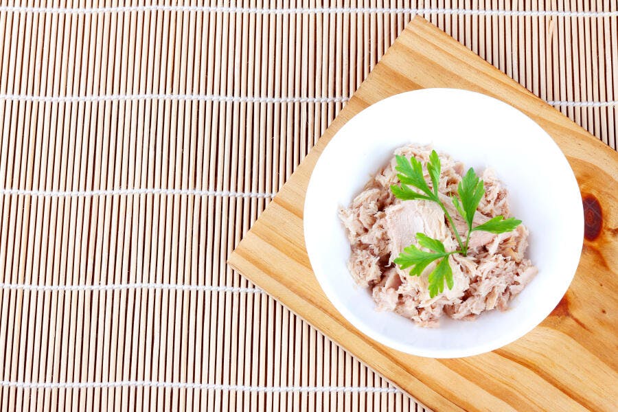 Tigela de atum desfiado com salsa fresca sobre esteira de bambu e tábua de madeira