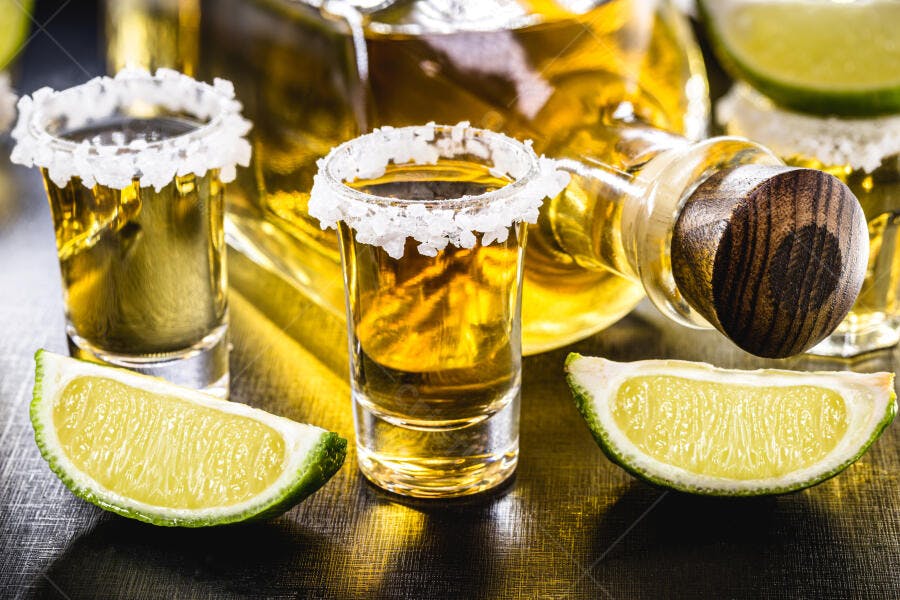 Copos de tequila dourada com sal na borda e fatias de limão fresco