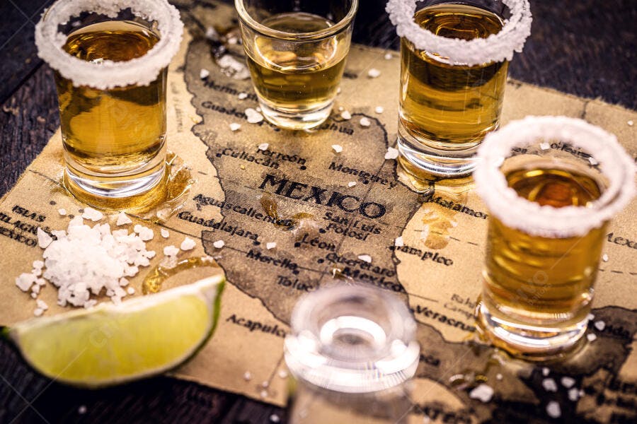 Tequila dourada com sal e limão sobre mapa vintage do México