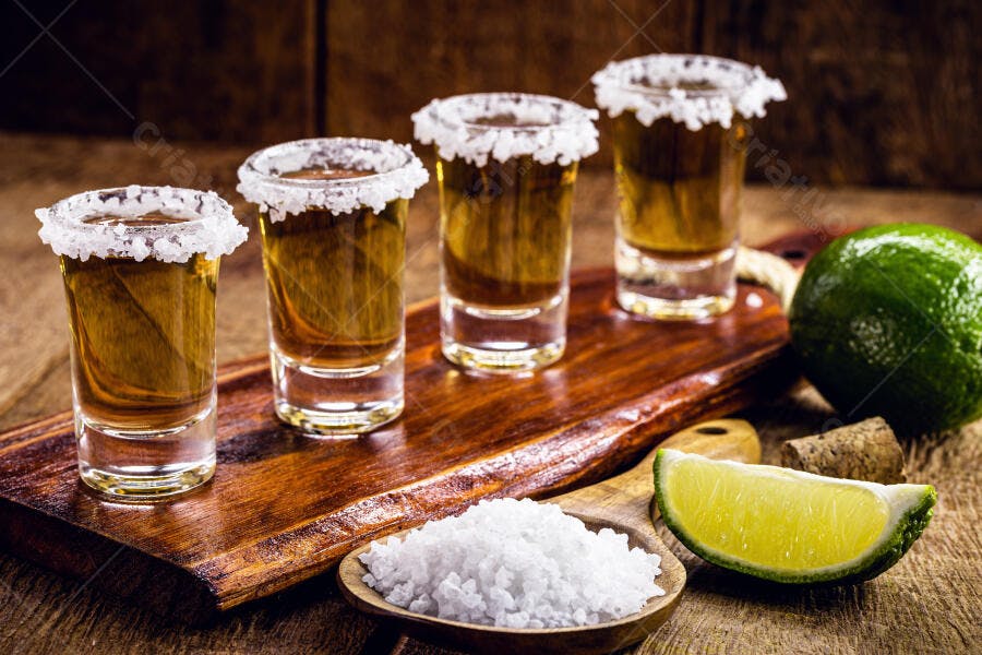 Tequila shots com sal e limão em tábua de madeira escura