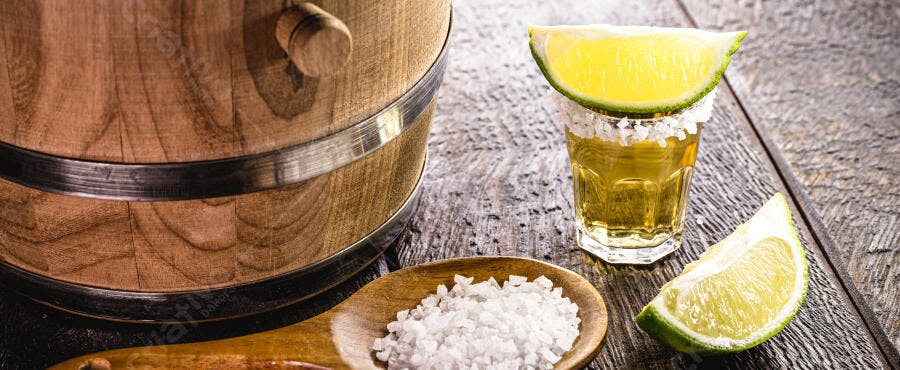 Tequila shot com limão e sal em mesa rústica de madeira e barril