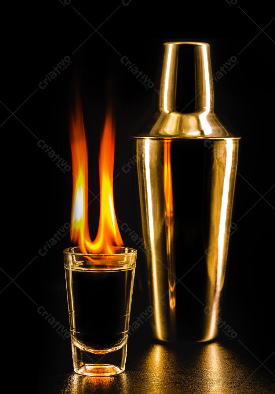 Shot de bebida flamejante e coqueteleira dourada em bar escuro