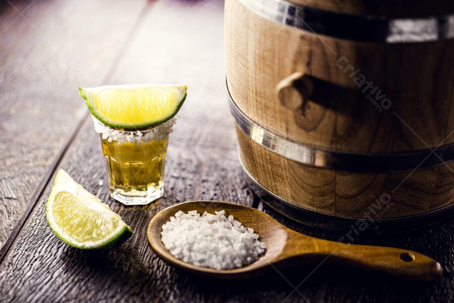 Tequila shot com limão e sal em mesa rústica de madeira e barril