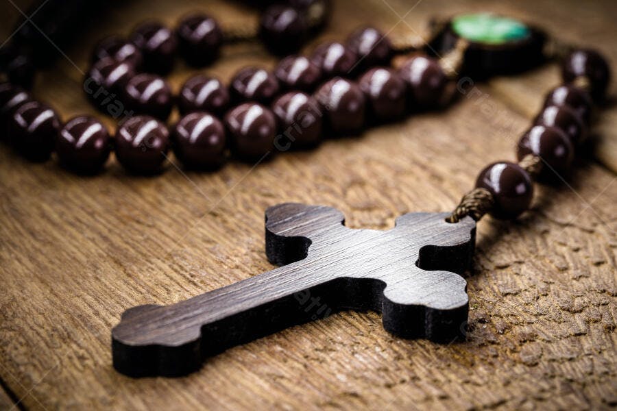Rosário de contas marrons e cruz de madeira sobre mesa rústica