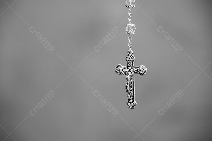 Prata rosário e crucifixo católico pendurado fundo cinza desfocado