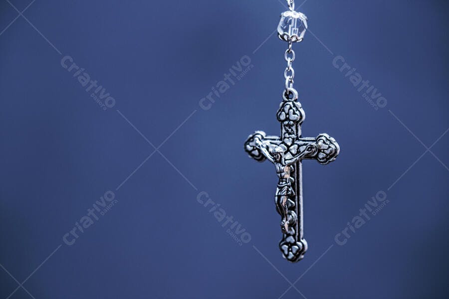 Crucifixo de prata com rosário em fundo azul profundo