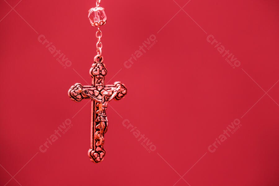 Crucifixo dourado de rosário em fundo vermelho vibrante