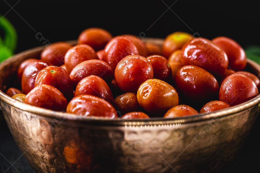 Tomates cereja frescos com gotas de água em tigela de cobre rústica sobre fundo escuro