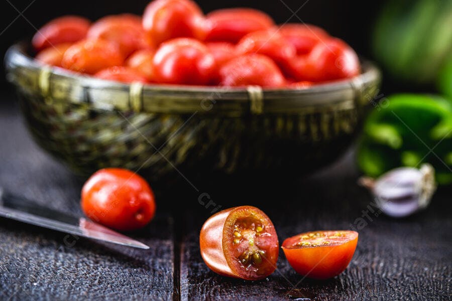 Tomates cereja frescos cortados e inteiros em tigela rústica com vegetais