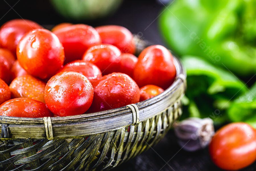 Tomates frescos vermelhos em cesto de vime com gotas de água