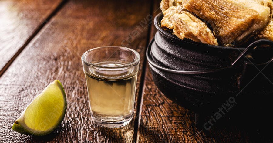Cachaça com limão e torresmo crocante em panela de ferro na mesa de madeira