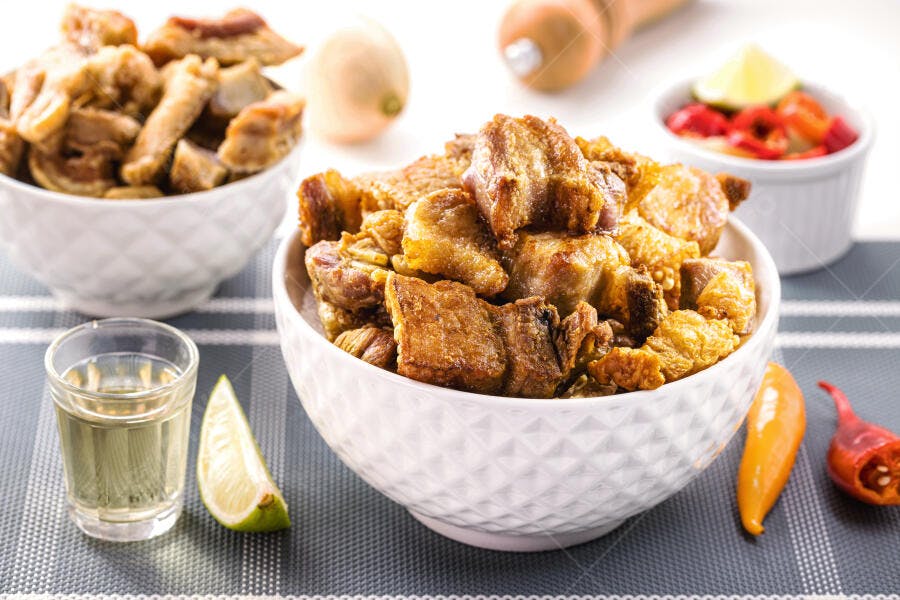Torresmo crocante dourado com cachaça limão e pimenta em mesa rústica