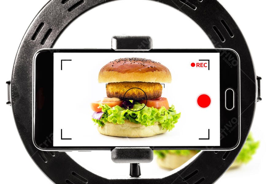 Hambúrguer vegano sendo gravado por smartphone com ring light