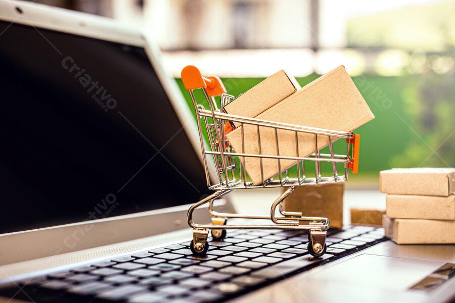 Carrinho de compras miniatura com caixas em teclado de notebook comprando online