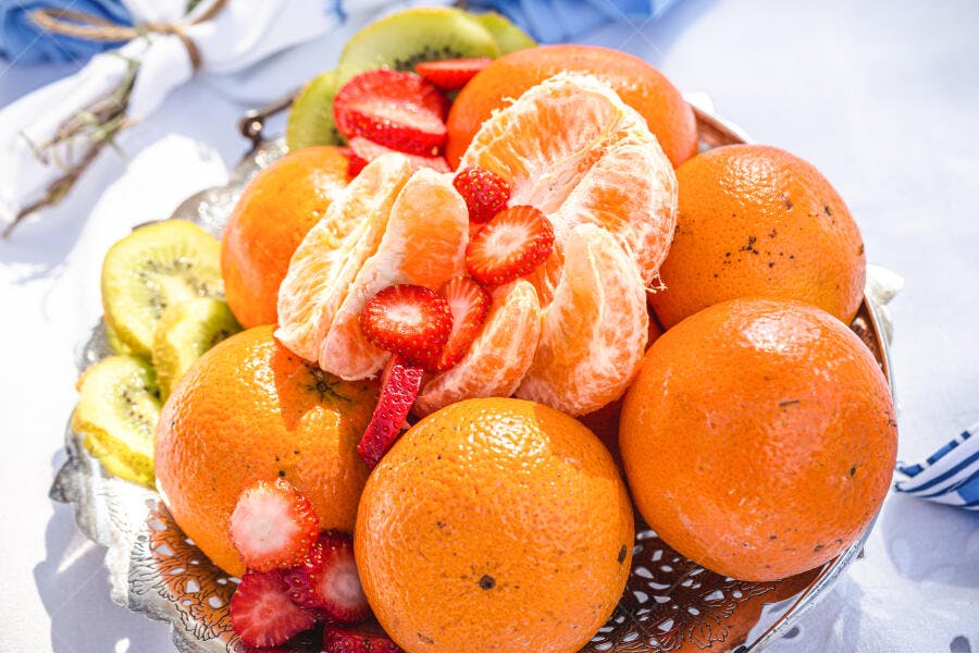 Frutas frescas vibrantes laranjas morangos e kiwi em fruteira decorada