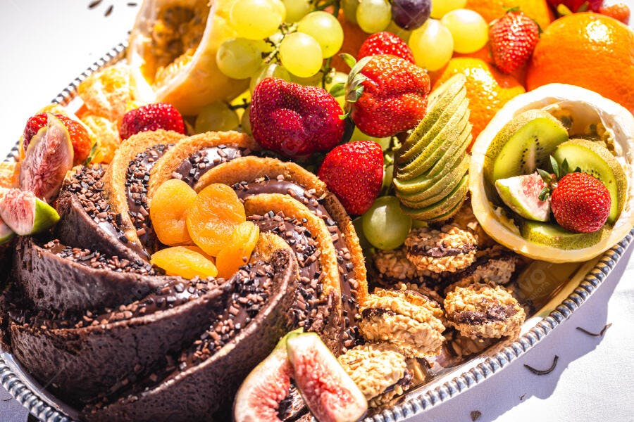 Bolo de chocolate decorado com frutas frescas vermelhas e verdes em bandeja de sobremesas