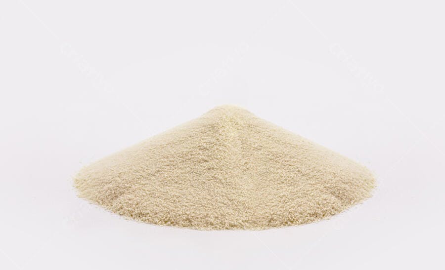Pó granular bege em montinho sobre fundo branco liso
