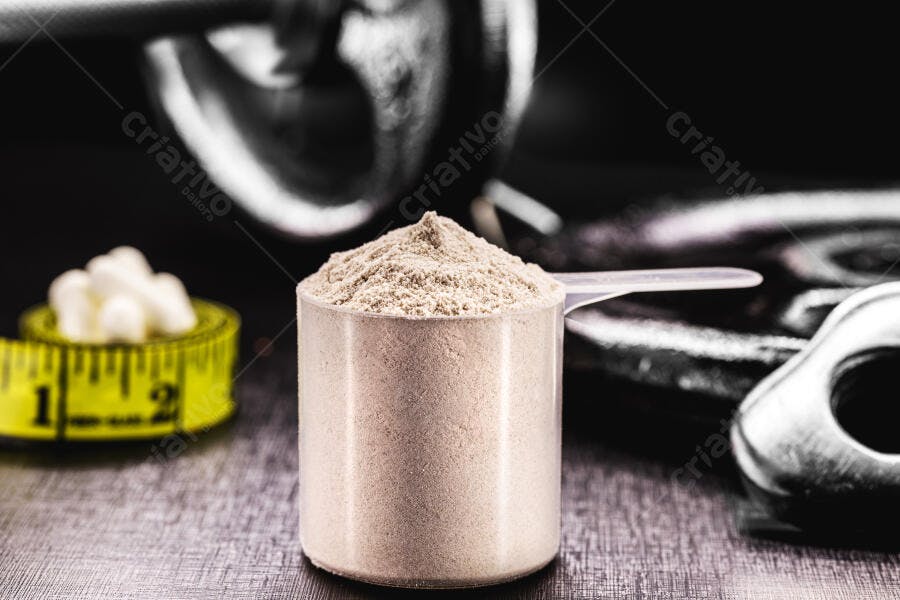Pó de proteína em medida com fita métrica e haltere em fundo escuro