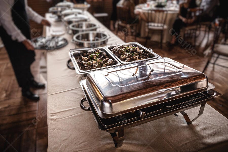 Buffet de comida quente em evento elegante com garçom profissional