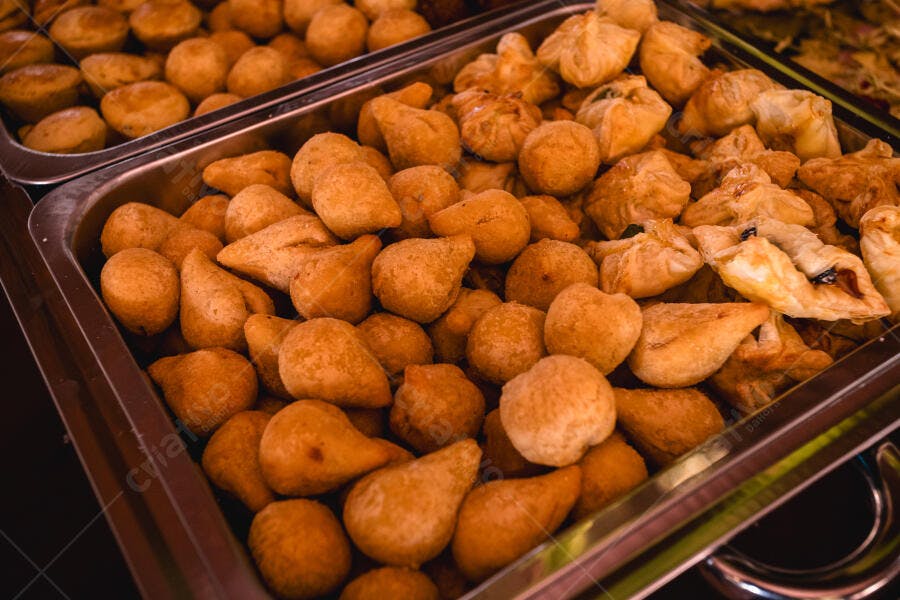 Coxinhas e salgados variados fritos dourados em bandejas de buffet
