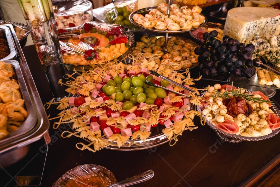 Buffet de aperitivos com queijos, uvas verdes e frios em mesa de festa