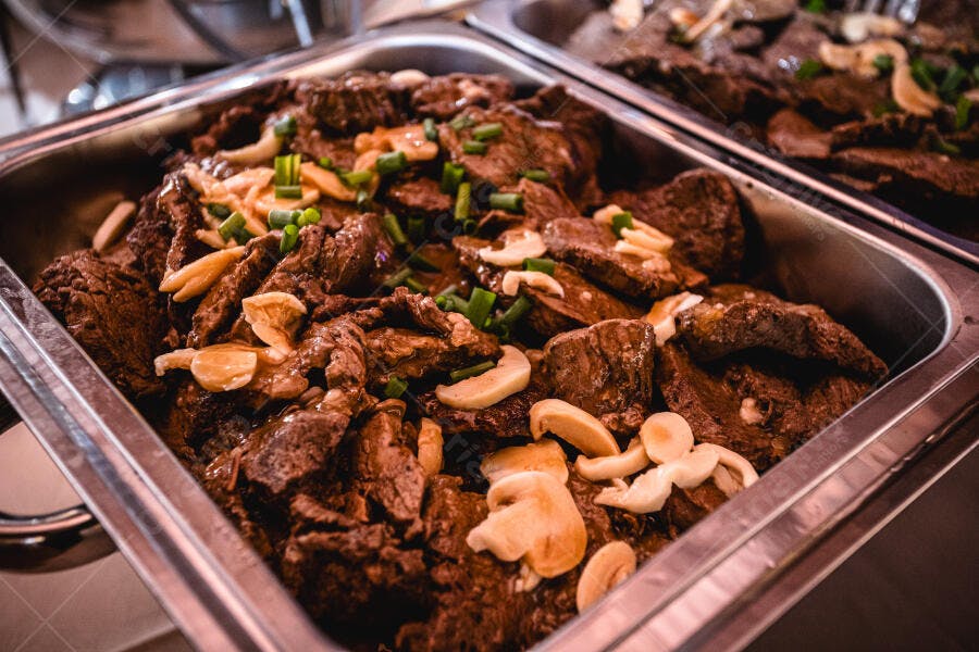 Carne de panela com cogumelos e cebolinha em bandeja de buffet para evento