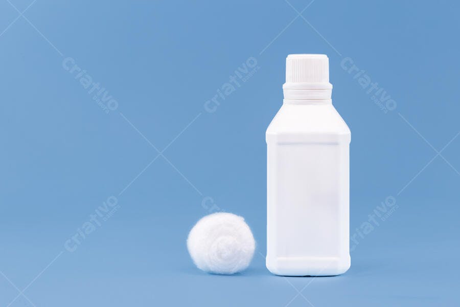 Garrafa plástica branca e algodão redondo sobre fundo azul claro
