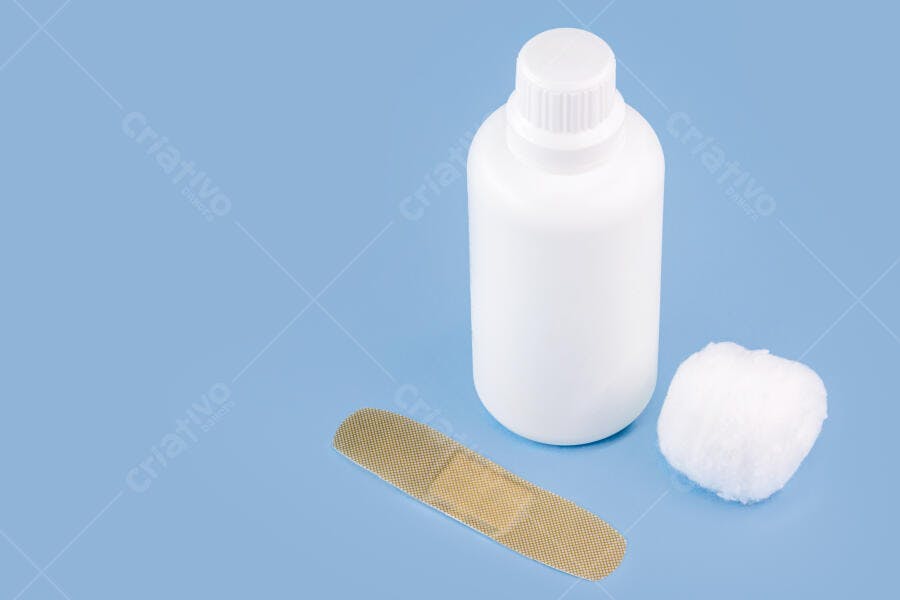 Kit de primeiros socorros com frasco branco, algodão e curativo em fundo azul claro