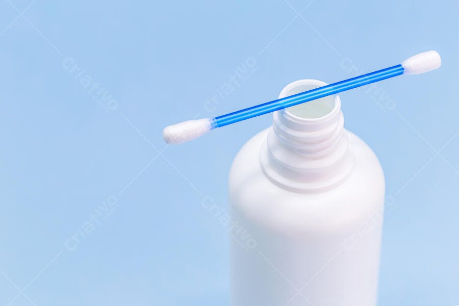 Cotonete azul e branco sobre frasco de plástico para higiene pessoal