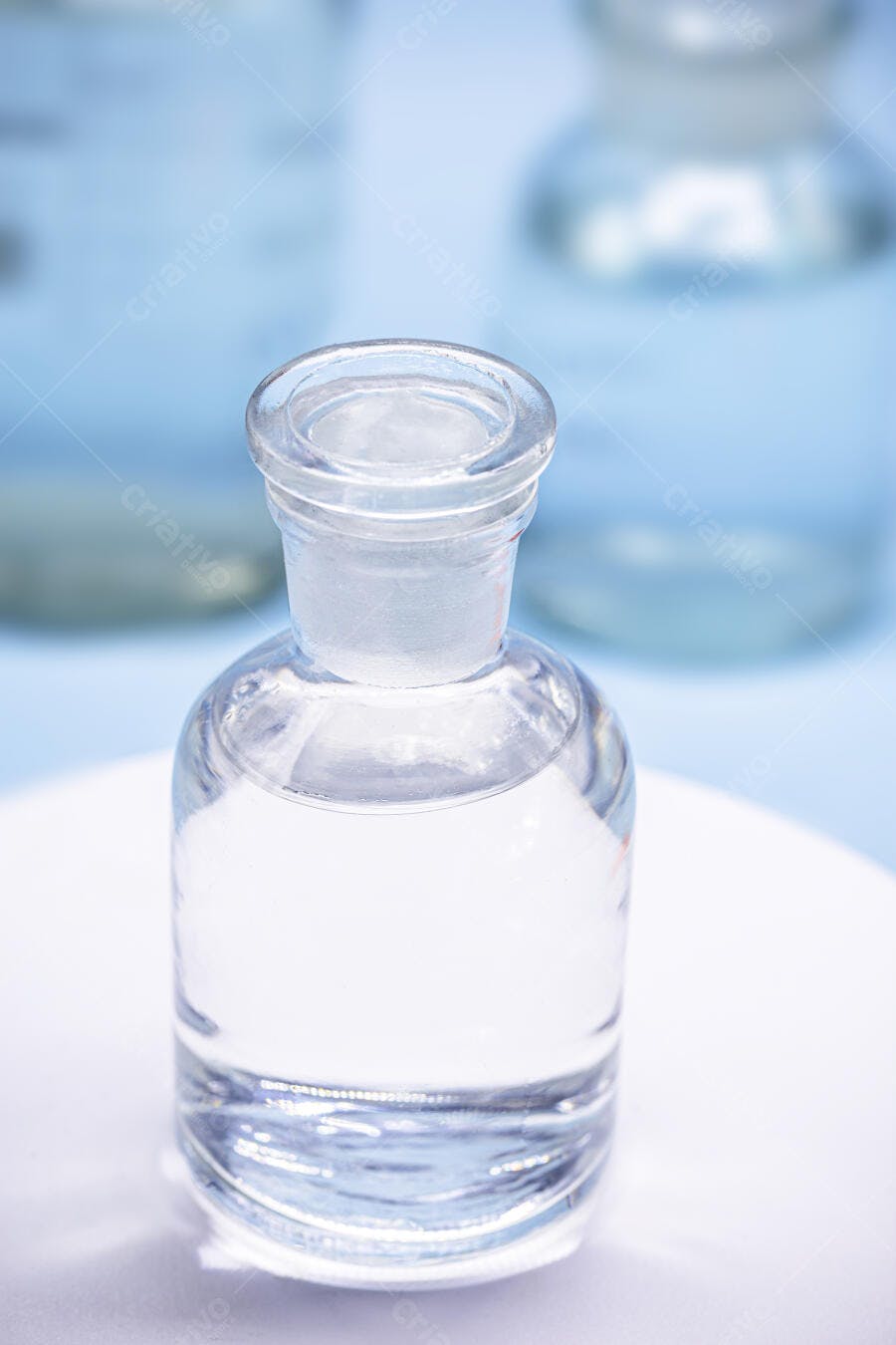 Frasco de vidro transparente com líquido em laboratório azul