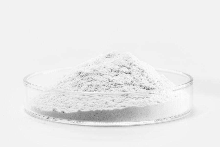 Pó branco granulado em placa de petri de laboratório fundo branco