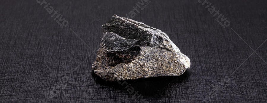 Rocha escura com textura áspera em fundo preto isolado