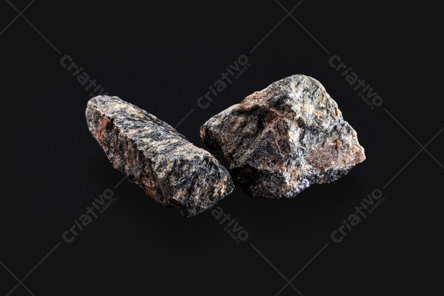 Rochas minerais brutas com textura escura em fundo preto isolado