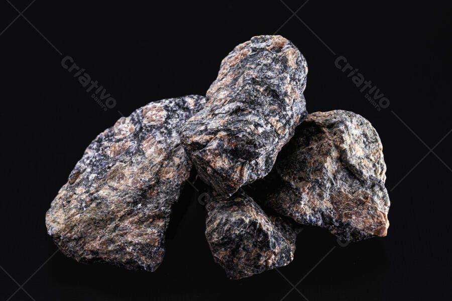 Rochas minerais escuras com textura áspera em fundo preto