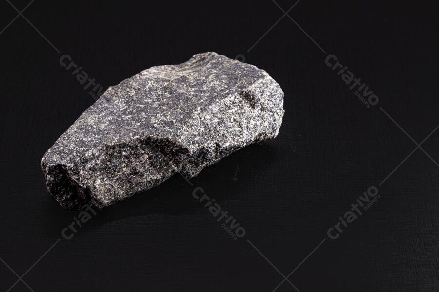 Rocha cinza escura com textura áspera em fundo preto isolado